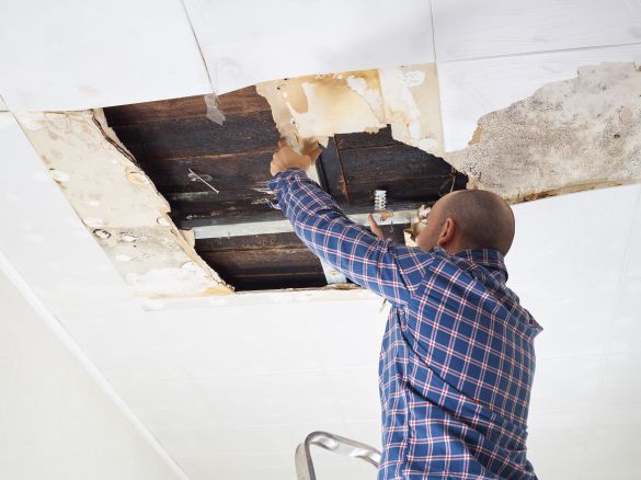 Man fixing water damaged ceiling