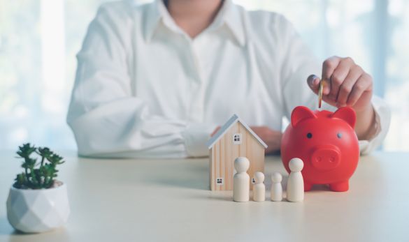 A women putting a coin in a red piggy bank